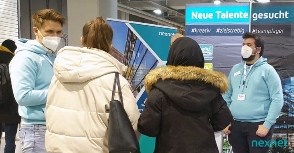 The picture shows schoolgirls talking to nexnet employees and trainees at the booth.