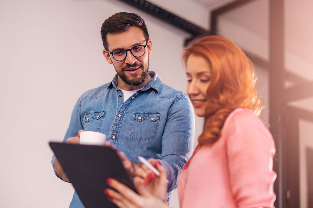 Abonnements verwalten. Nutzen Sie dazu nexnet.cloud unsere Lösung für Subscription Billing. Das Bild zeigt einen Mann und eine Frau, die nebeneinander stehen und auf ein Tablet blicken. Sie stehen in einem Büro und besprechen, was sie auf dem Tablet sehen.