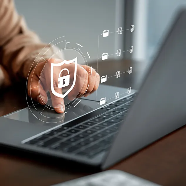 Finger tippt auf ein Hologramm mit Sicherheitssymbol und Schloss über einem Laptop, daneben digitale Ordnerstrukturen als Symbol für IT-Sicherheitskonzepte und Datenschutz.