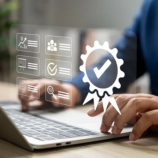 Person arbeitet an einem Laptop, während ein digitales Hologramm mit Symbolen für Qualitätsmanagement, Zertifizierung und Kontrolle über der Tastatur eingeblendet ist.