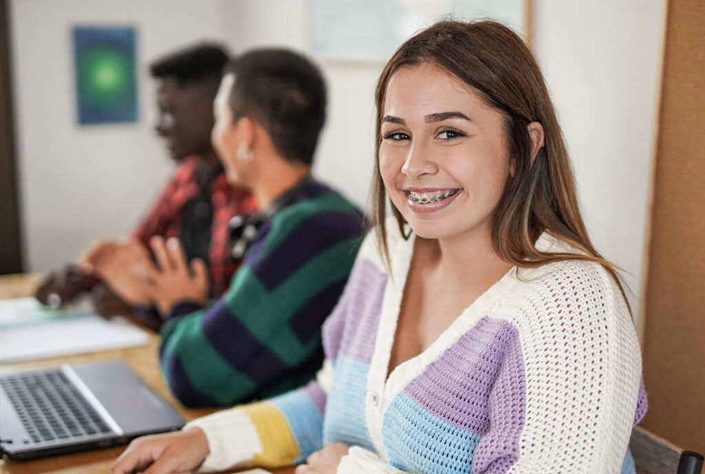 Auf dem Bild sind Schüler zu sehen. Im Vordergrund ein junges Mädchen, dass in die Kamera schaut und sich auf den Girls Day freut.