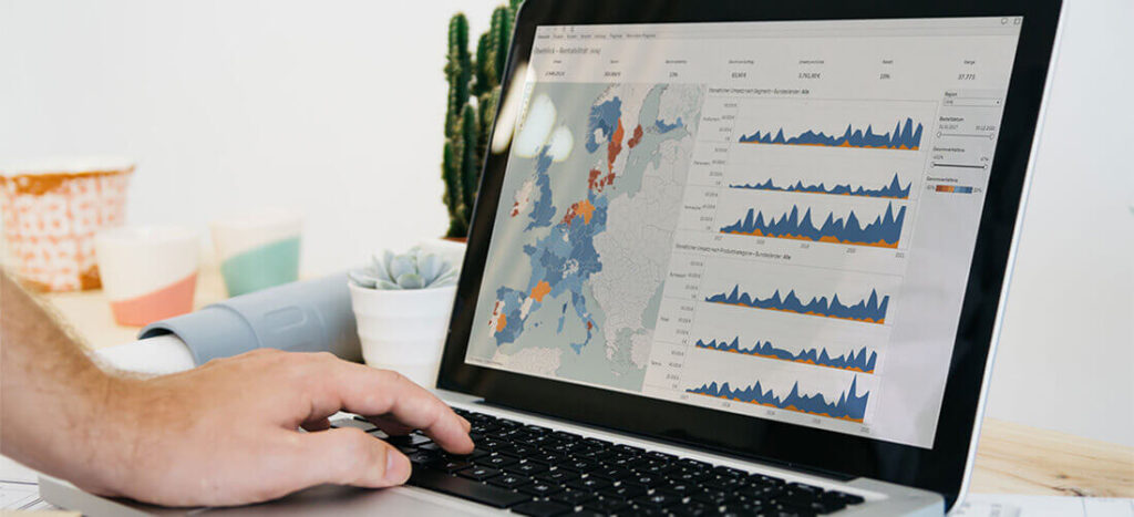 MRR-Reporting, Linke Hand tippt auf Laptop, Grafik über Reporting auf Bildschirm