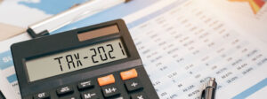 Taschenrechner im Vordergrund, Steuerunterlagen im Hintergrund