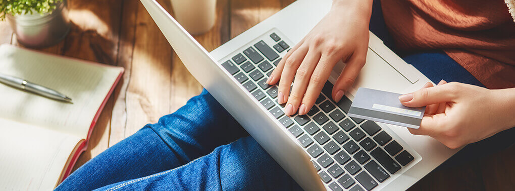 Eine Person hat einen Laptop auf dem Schoß und tippt auf der Tastatur.