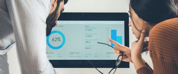 Was ist Billing? Das Bild zeigt zwei Personen, die auf einen Bildschirm blicken und die Daten und Grafiken darauf analysieren.