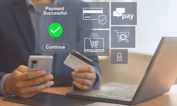 Einen Person sitz an einem Schreibtisch mit Laptop und Tablet vor ihr und Handy und Kreditkarte in der Hand. Übers Bild leicht ausgegraut dargestellt, werden Symbole des E-Commerce angezeigt, wie ein Einkaufswagen und eine Kreditkarte und ein Sicherheitsschloss, sowie die Benachrichtigung eines erfolgreichen Payments.