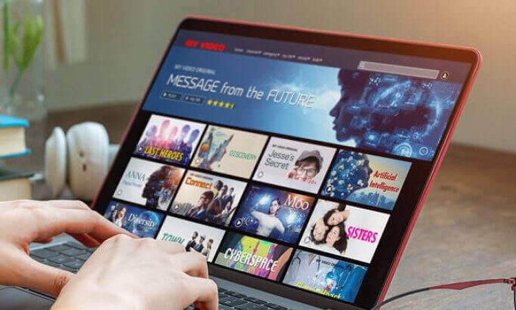 A subscription menu with various movies is displayed on a laptop.