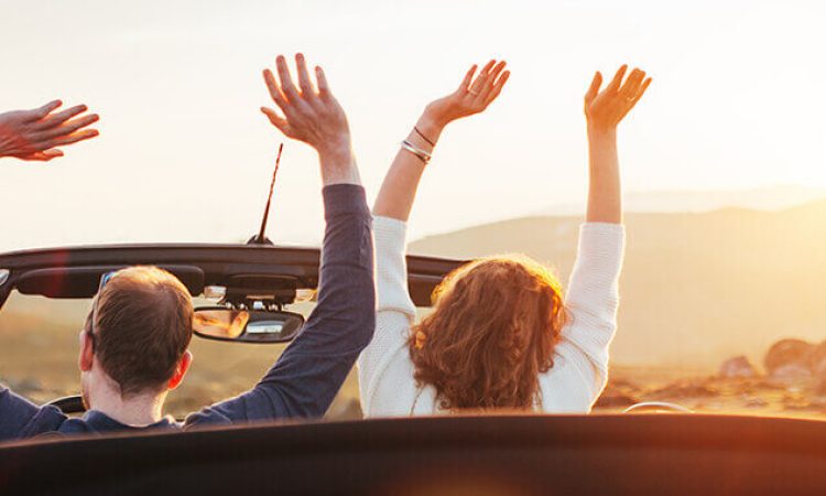 A couple sits happily in the Caprio and drives towards the sun.