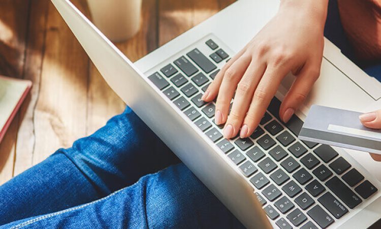 Eine Person hat einen Laptop auf dem Schoß und tippt auf der Tastatur.